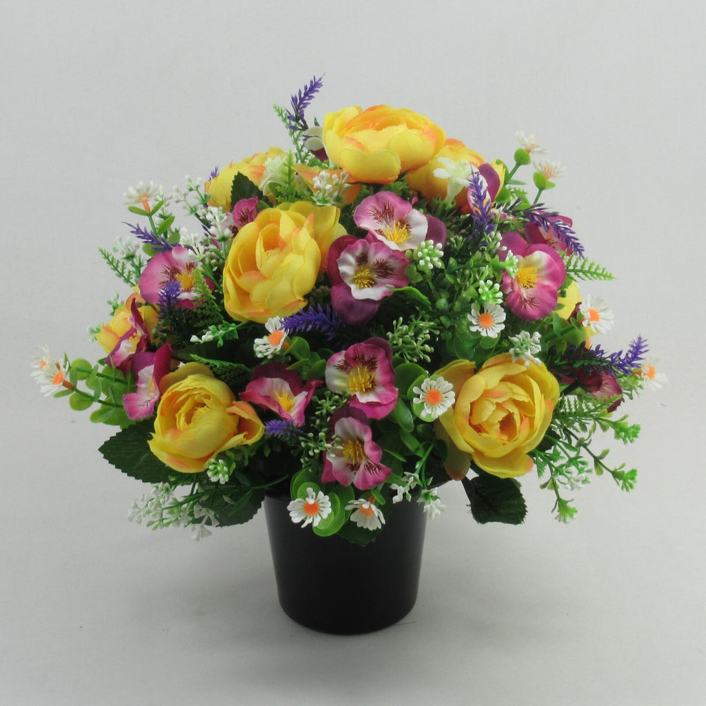 Memorial artificial flowers: yellow roses, purple sprigs, pink blooms in black pot