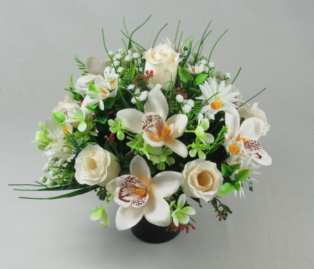 Artificial memorial flower arrangement in black pot with white roses, orchids, and green leaves