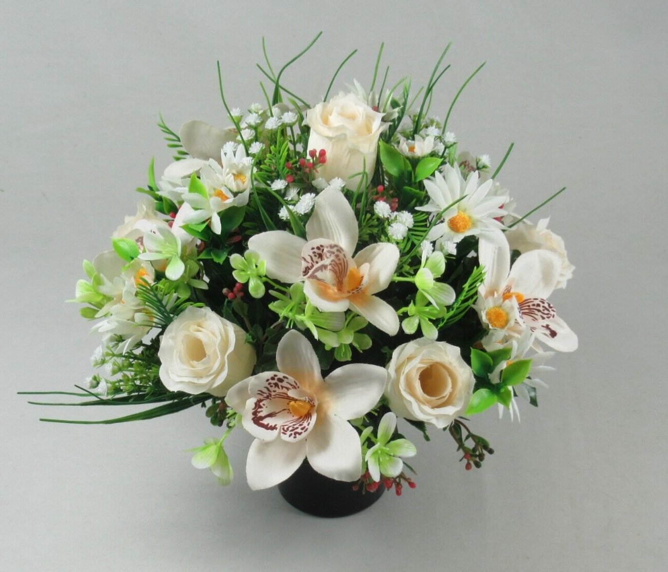 Artificial memorial flower arrangement in black pot with white roses, orchids, and green leaves