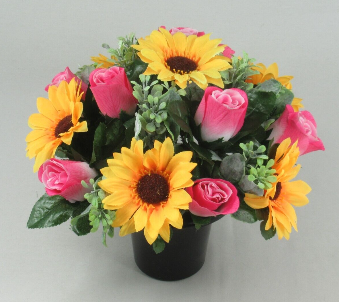Artificial memorial bouquet in black pot with yellow sunflowers, pink roses, and small greenery