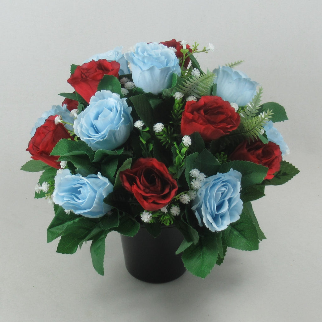 Artificial grave rose arrangement with red and light blue roses, white fillers, black pot