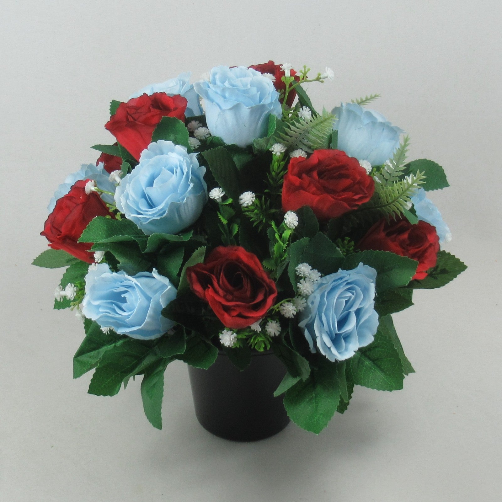 Artificial grave rose arrangement with red and light blue roses, white fillers, black pot