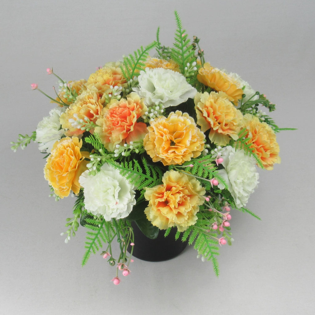 Angled artificial memorial flower arrangement in black crem pot with white and yellow blooms