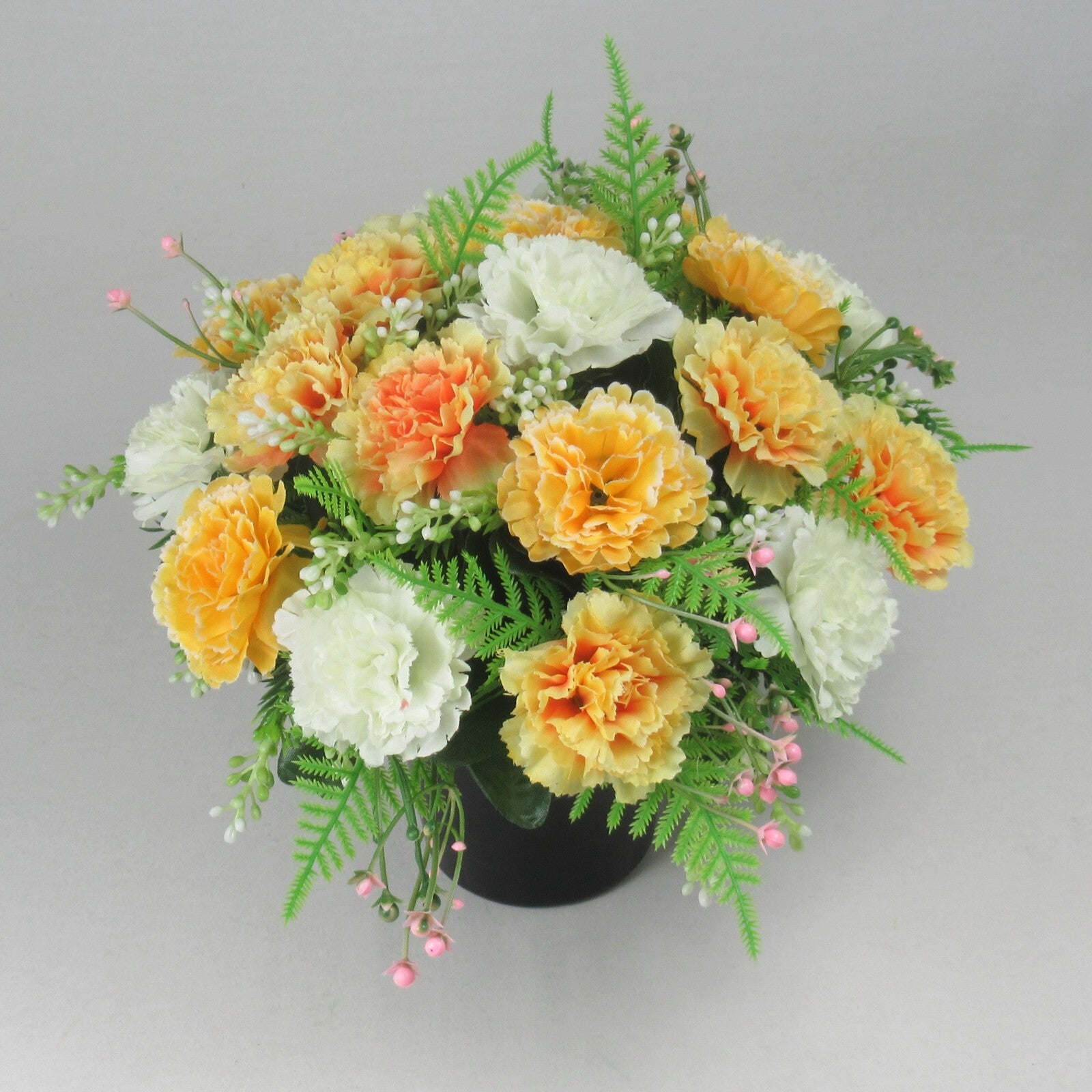 Angled artificial memorial flower arrangement in black crem pot with white and yellow blooms
