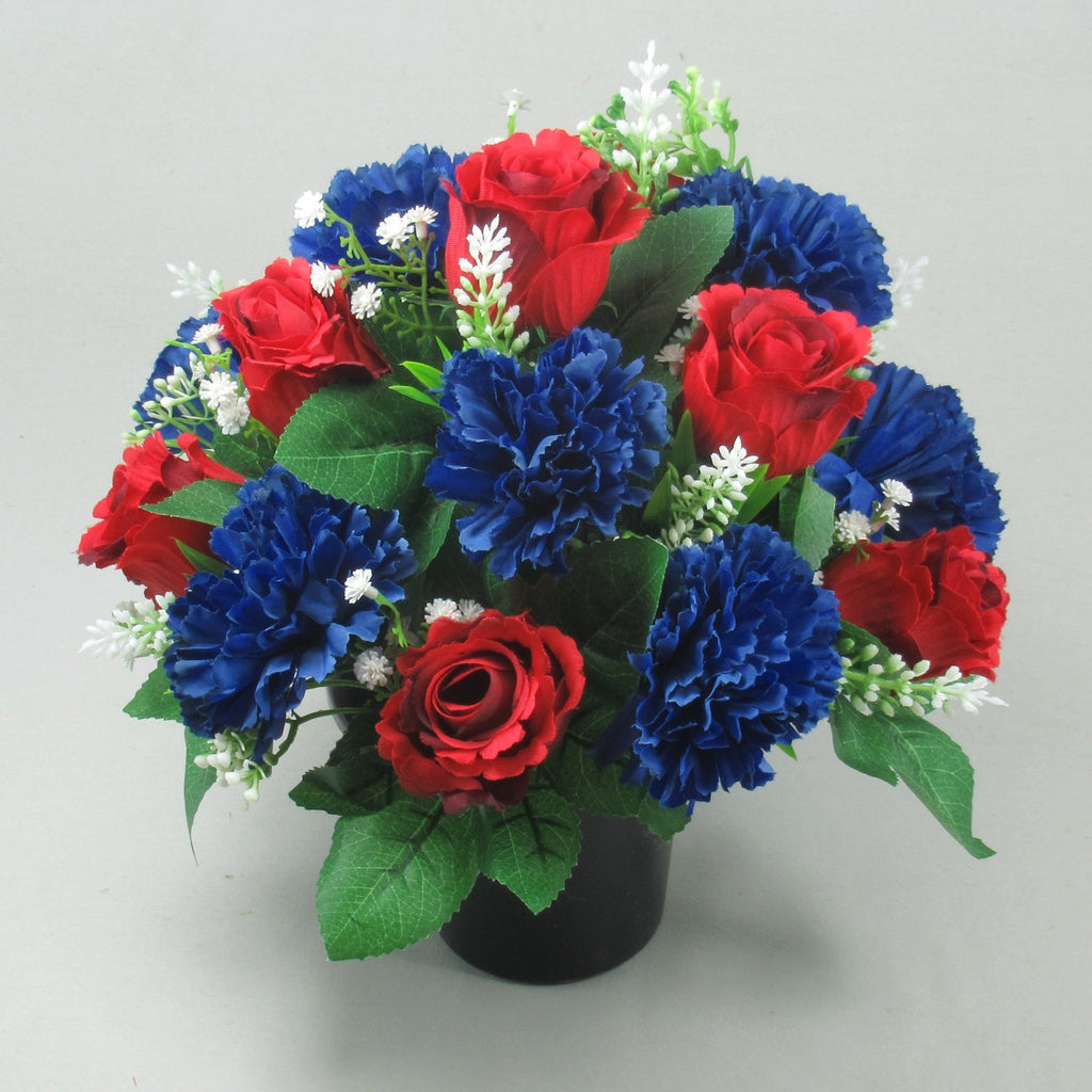 Dark pot grave arrangement of artificial roses and royal blue carnations with white buds