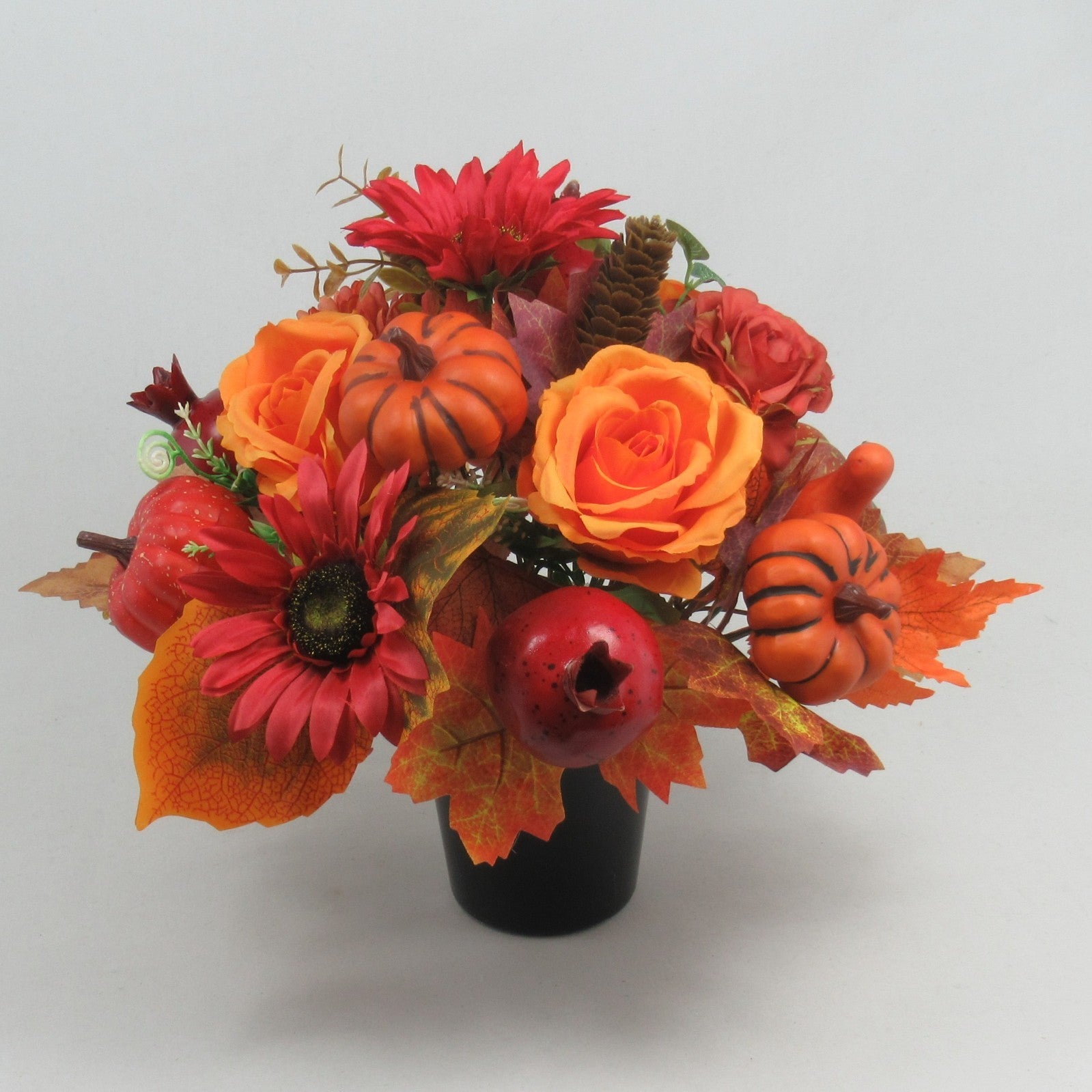 Autumn memorial gravepot arrangement: orange roses, red flowers, pumpkins and pomegranates in black pot