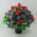 Handmade artificial memorial flowers: red roses, blue blooms, green foliage in black pot