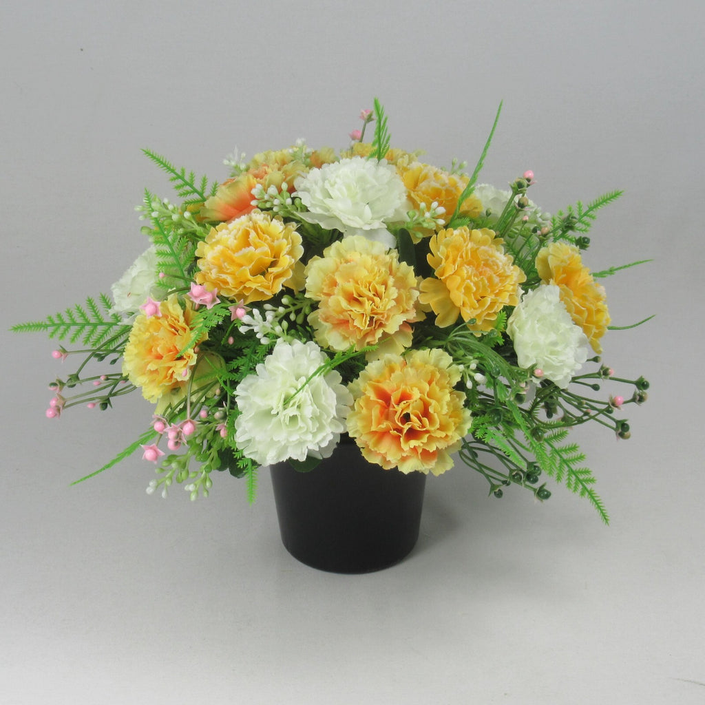 Round black crem pot grave arrangement of artificial silk flowers, yellow, orange, white and pink