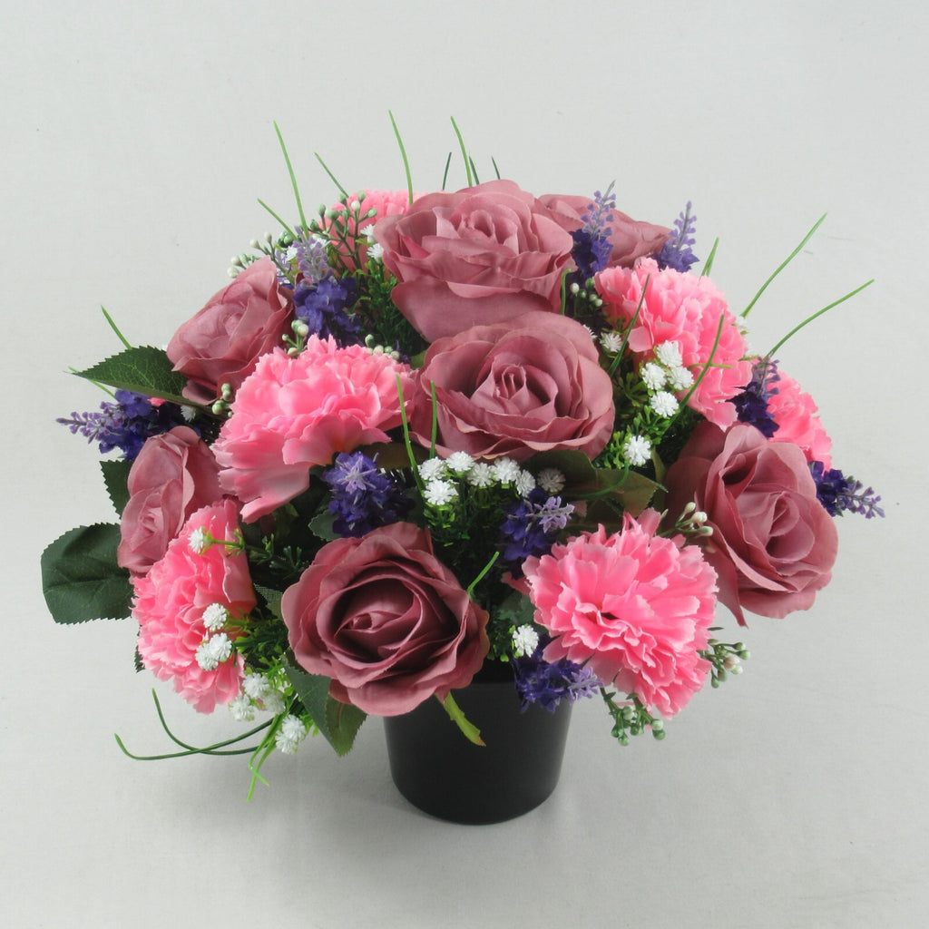 Artificial silk memorial cremation pot arrangement, pink carnations and mauve roses; purple sprigs