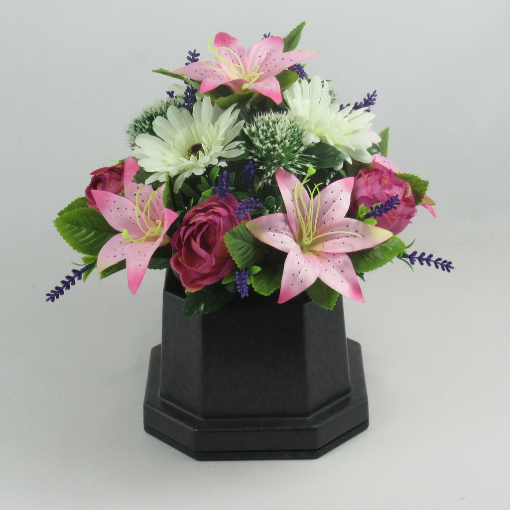 Memorial grave artificial flower arrangement in black pot with pink lilies, roses, white blooms.