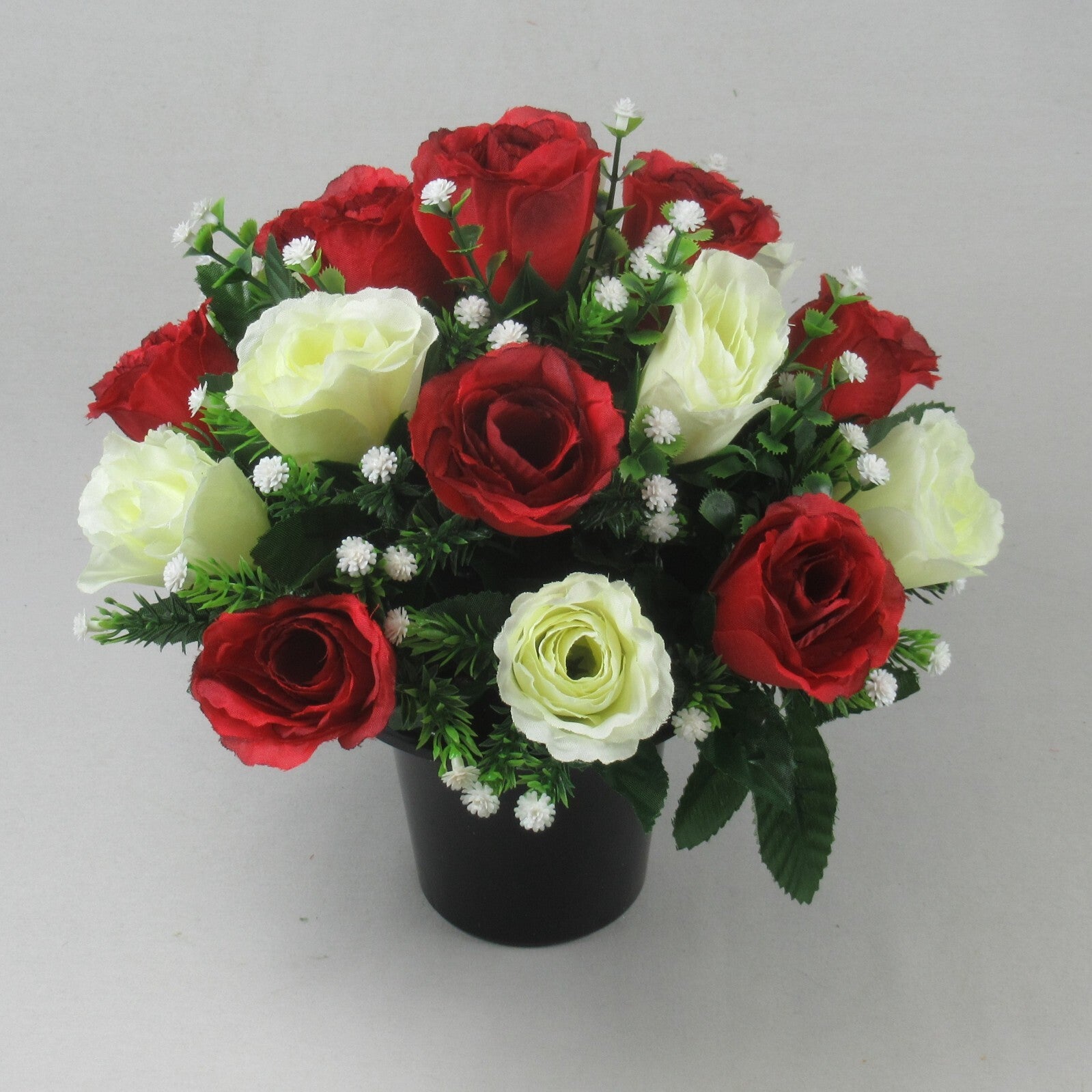 Red and ivory faux rose bouquet in black pot, green leaves and small white filler blooms