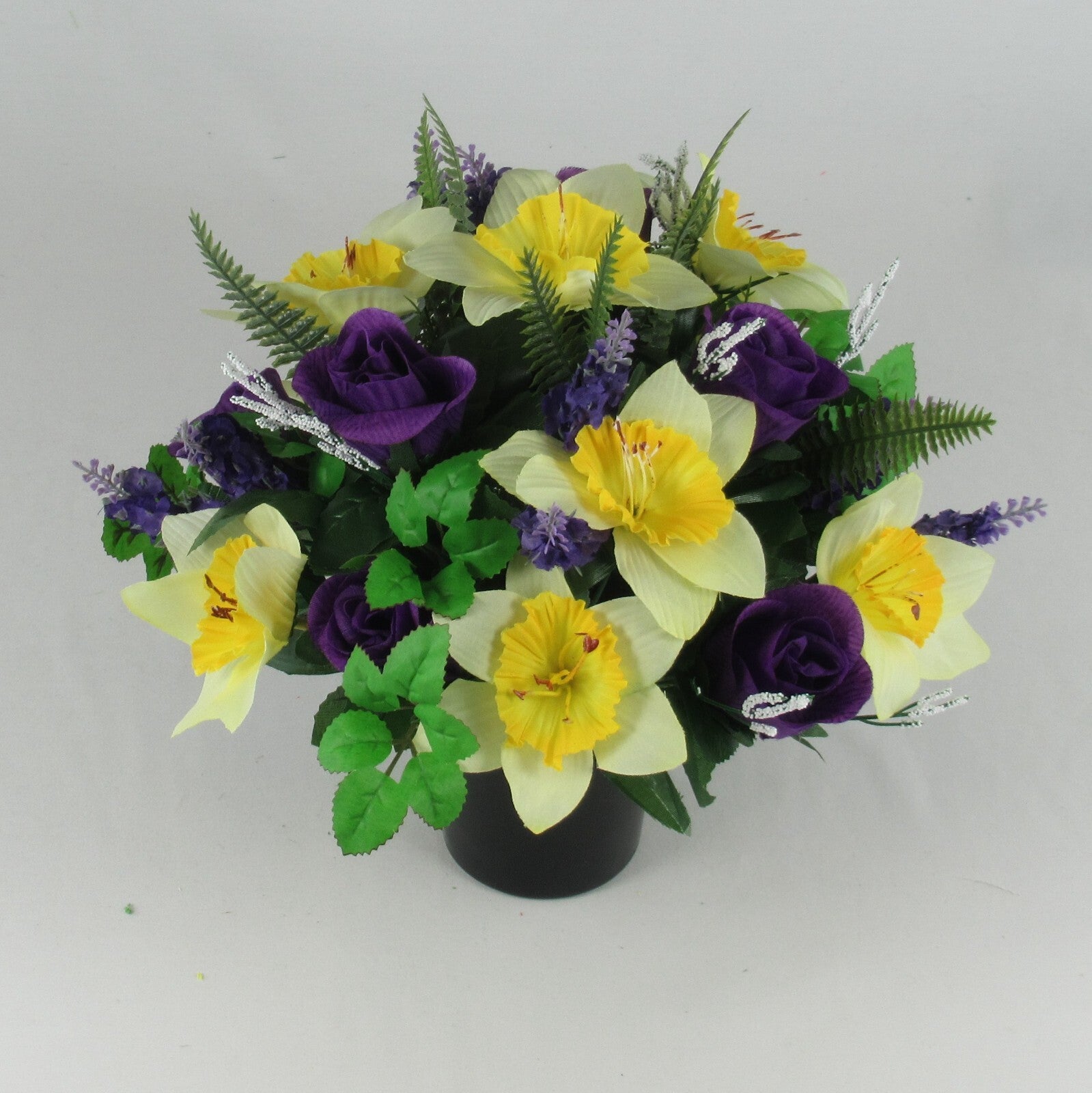 Memorial grave arrangement in black pot: yellow blooms, purple roses, silver stems, green leaves