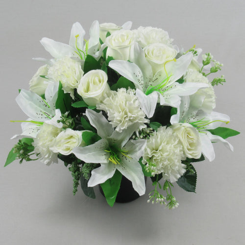 White artificial roses, lilies, and carnations in black memorial crem pot with greenery