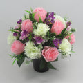 Memorial grave flower arrangement in black vase, pink roses, white carnations, purple blooms