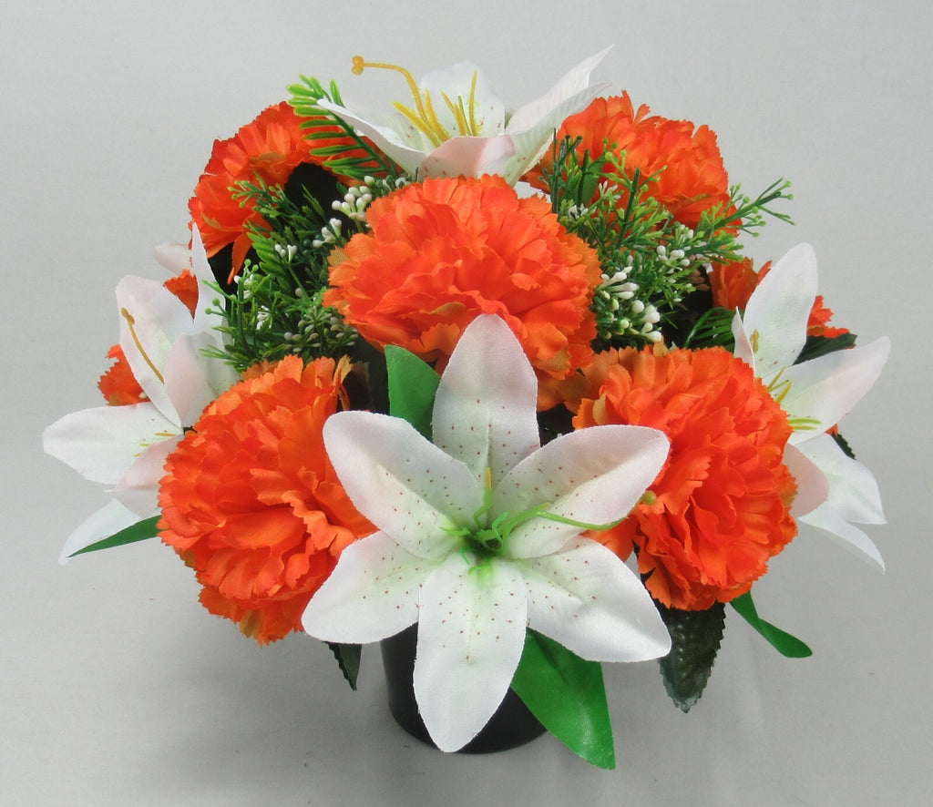 Front view of orange carnations and white lilies with green leaves in black pot