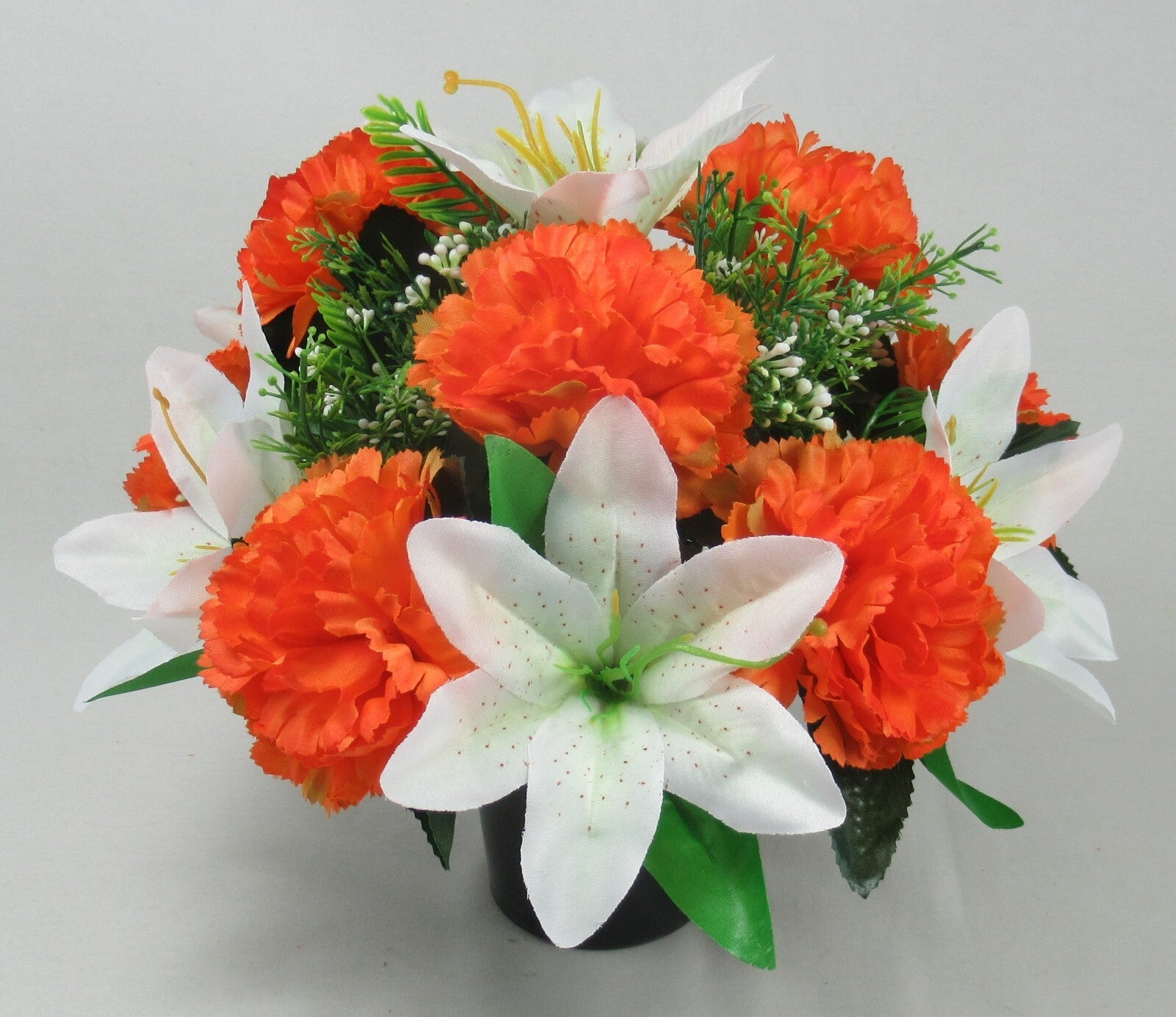 Front view of orange carnations and white lilies with green leaves in black pot
