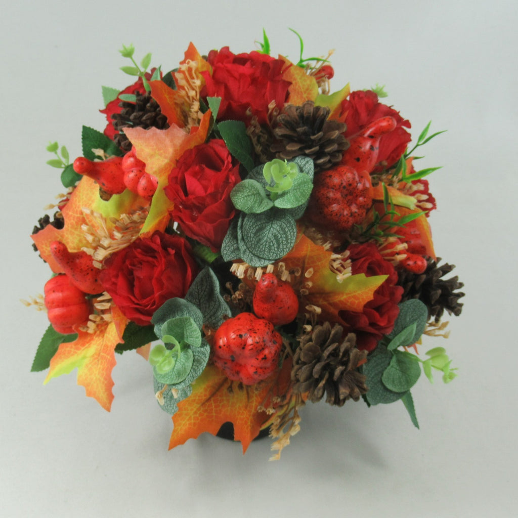 Warm autumn floral arrangement: red roses with pinecones, speckled berries, green leaves, in pot