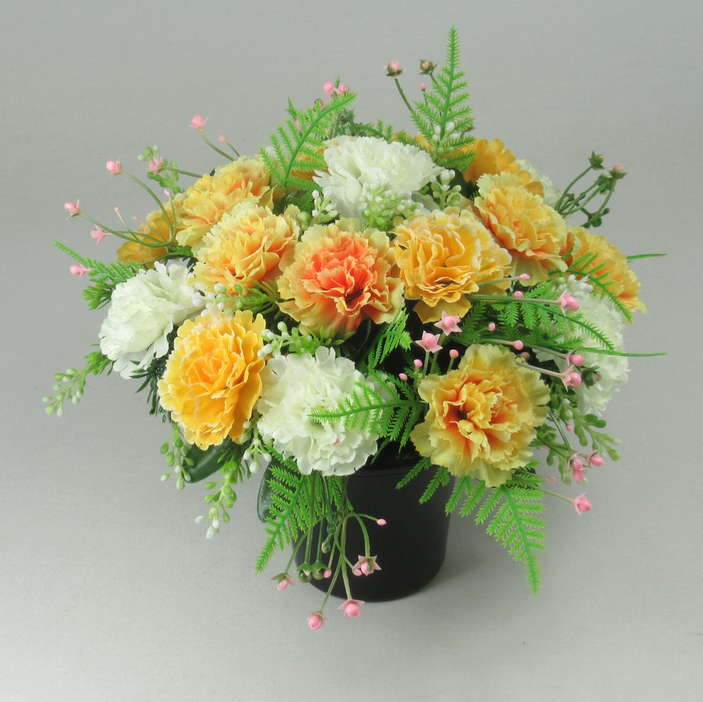 Close-up black crem pot arrangement with artificial silk blooms in orange, yellow, white, pink