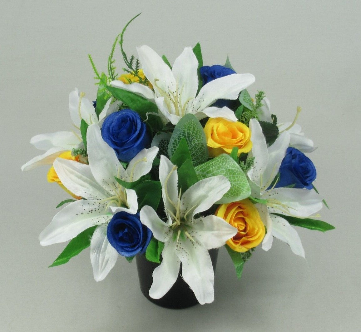 Artificial silk memorial pot arrangement: white lilies, blue roses, yellow roses with green leaves