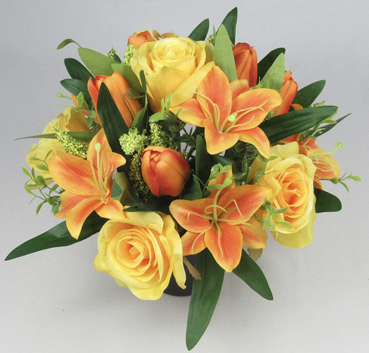 Artificial memorial grave bouquet with yellow, orange open roses and lily blooms, green leaves