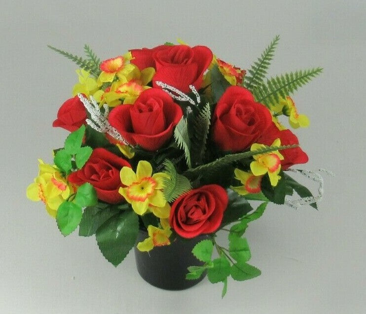 Angled artificial memorial bouquet with red roses, yellow flowers, and green foliage in black pot