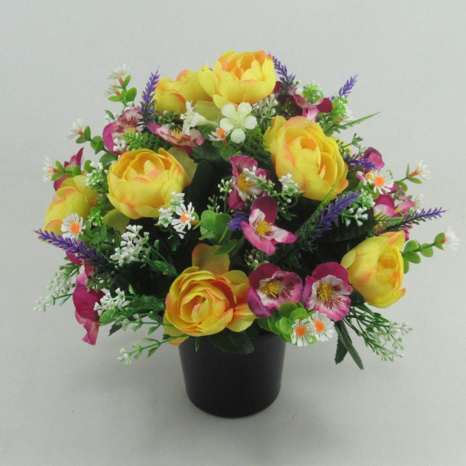 Artificial flowers with yellow roses, pink-violet blooms, white daisies in black vase