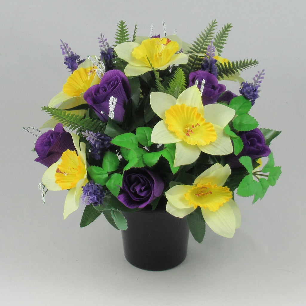 Memorial grave pot bouquet with large yellow flowers, purple rosebuds, green fern leaves—artificial