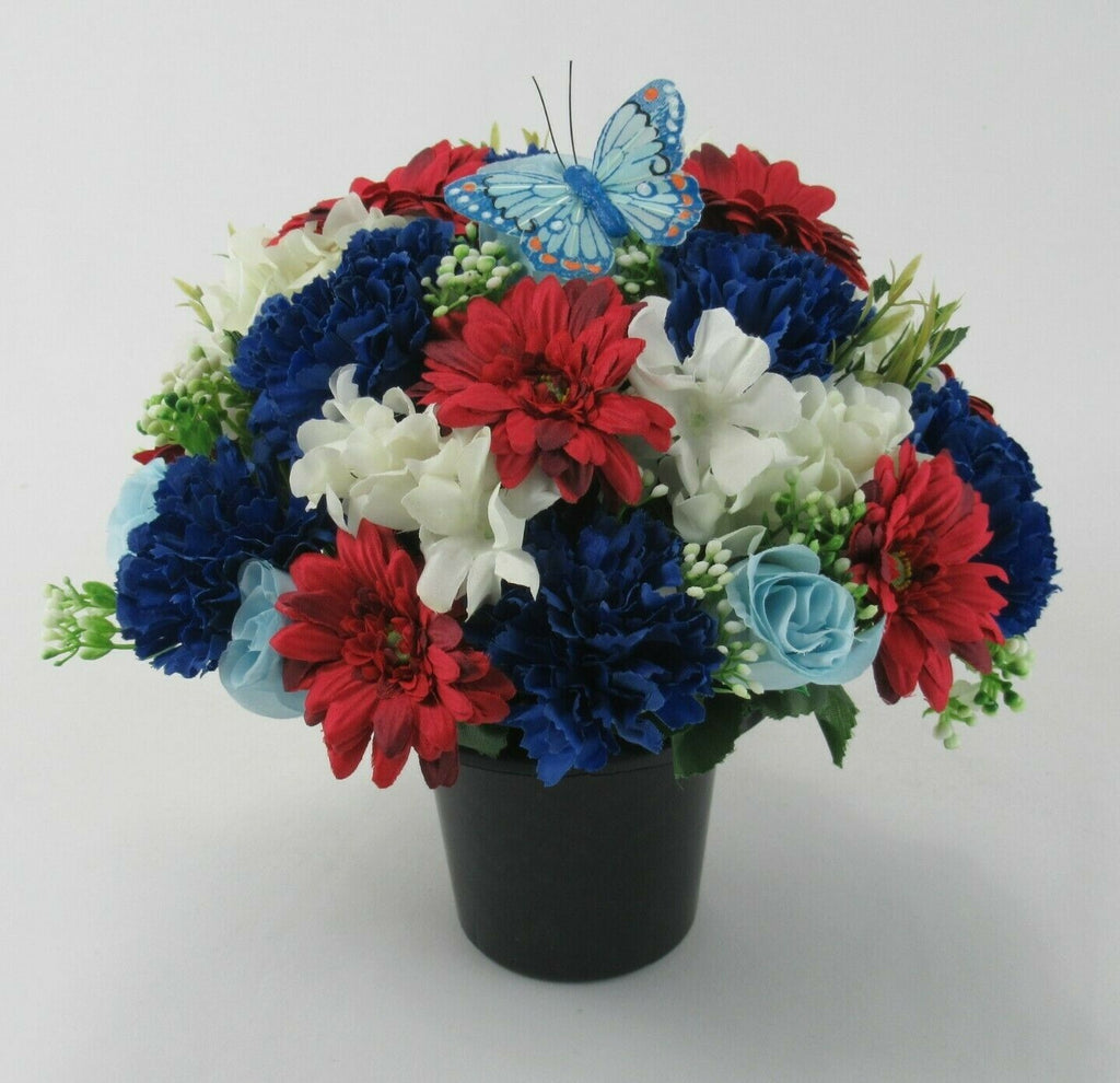 Memorial grave arrangement of red, royal-blue and white artificial flowers in black pot, butterfly