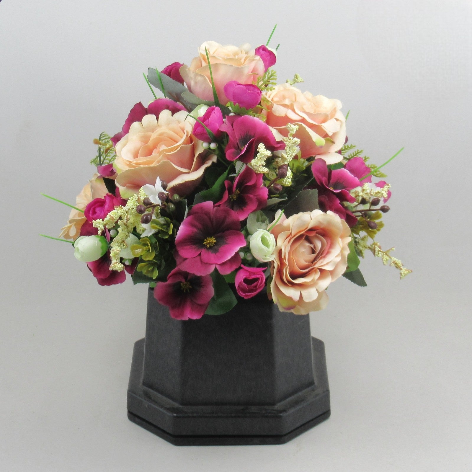 Artificial flower arrangement on black vase: cream roses, magenta petals, pale greenery