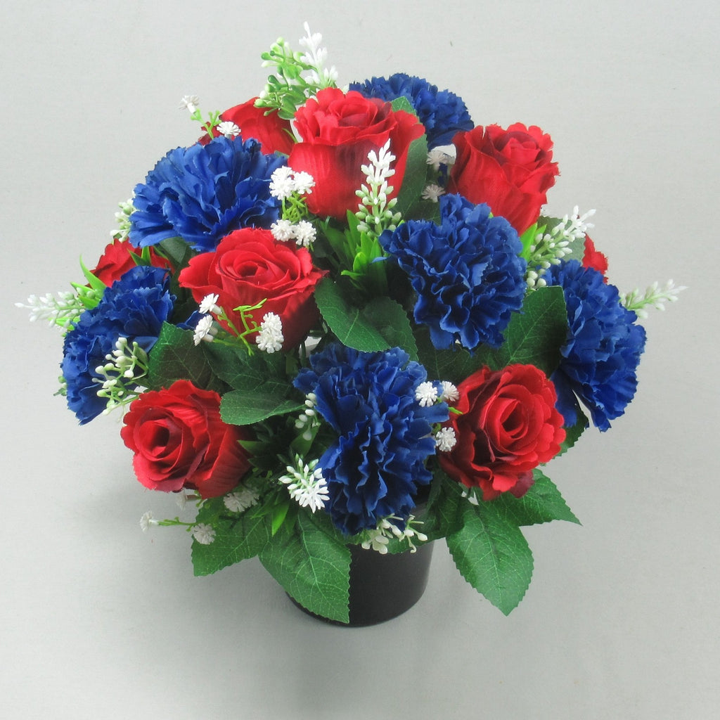 Memorial artificial flowers in dark pot: red roses, royal blue blooms, green leaves