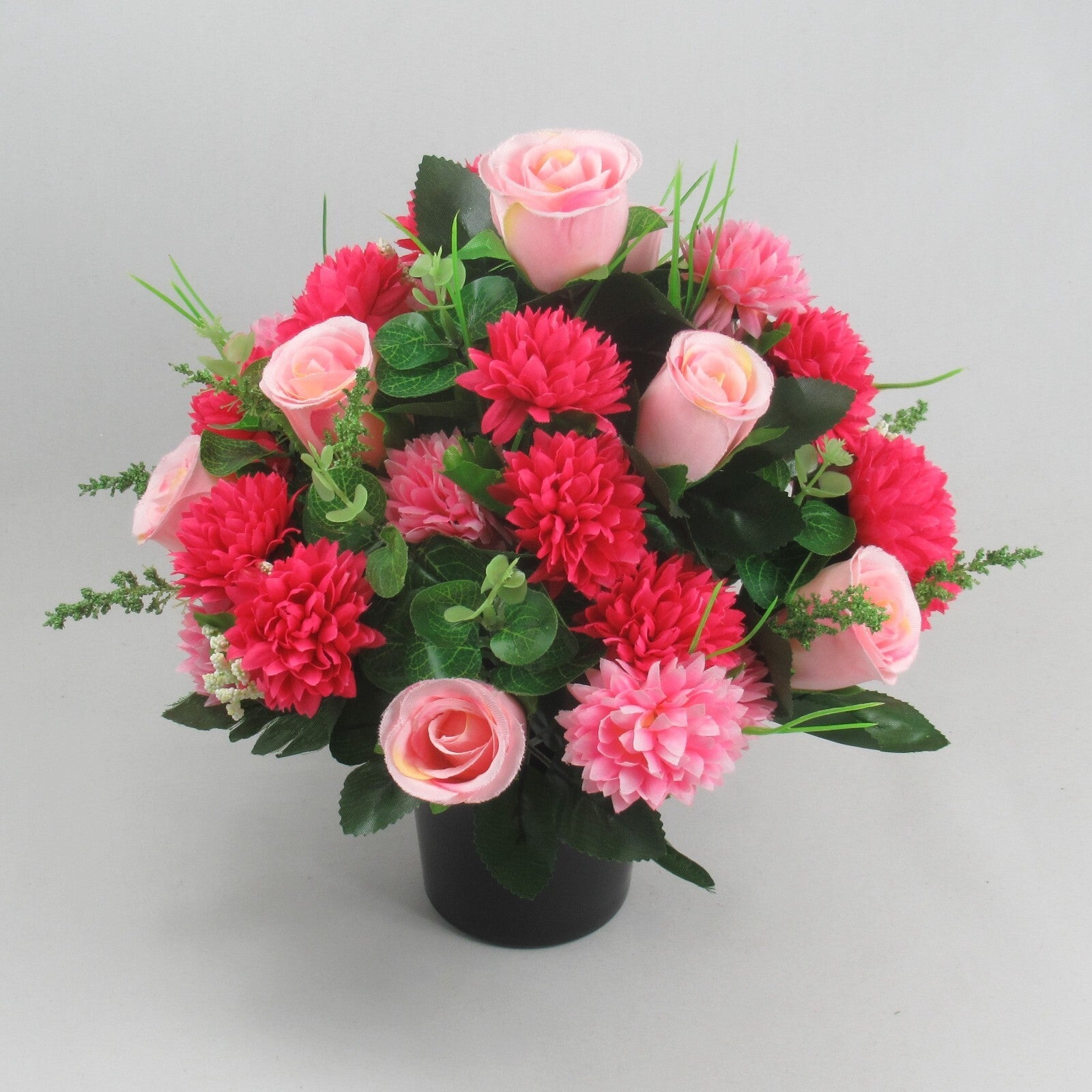 Memorial artificial arrangement in black pot with mixed pink roses, red-pink blooms, leaf sprigs