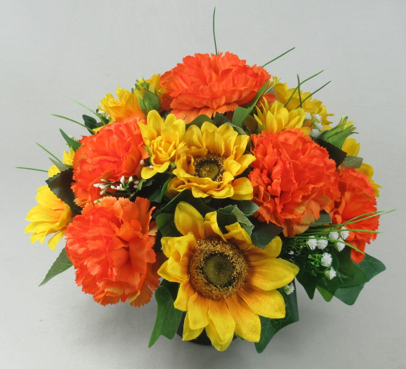 Artificial flower memorial pot with orange carnations, yellow sunflowers, and white blossom details