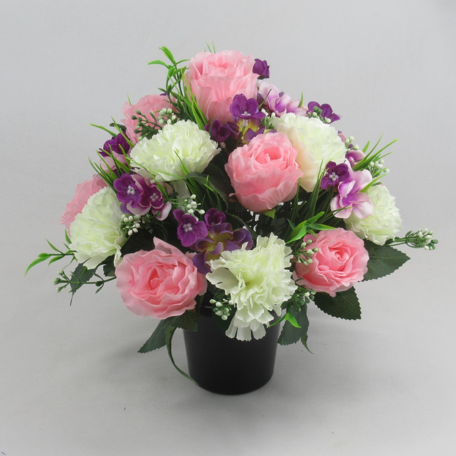 Artificial silk bouquet with pink and pale roses, white flowers, purple accents in black pot