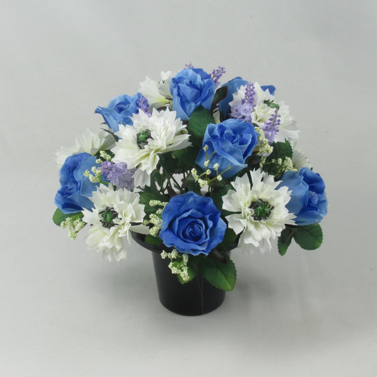 Artificial silk grave bouquet with blue roses and white blooms in black pot, green foliage accents