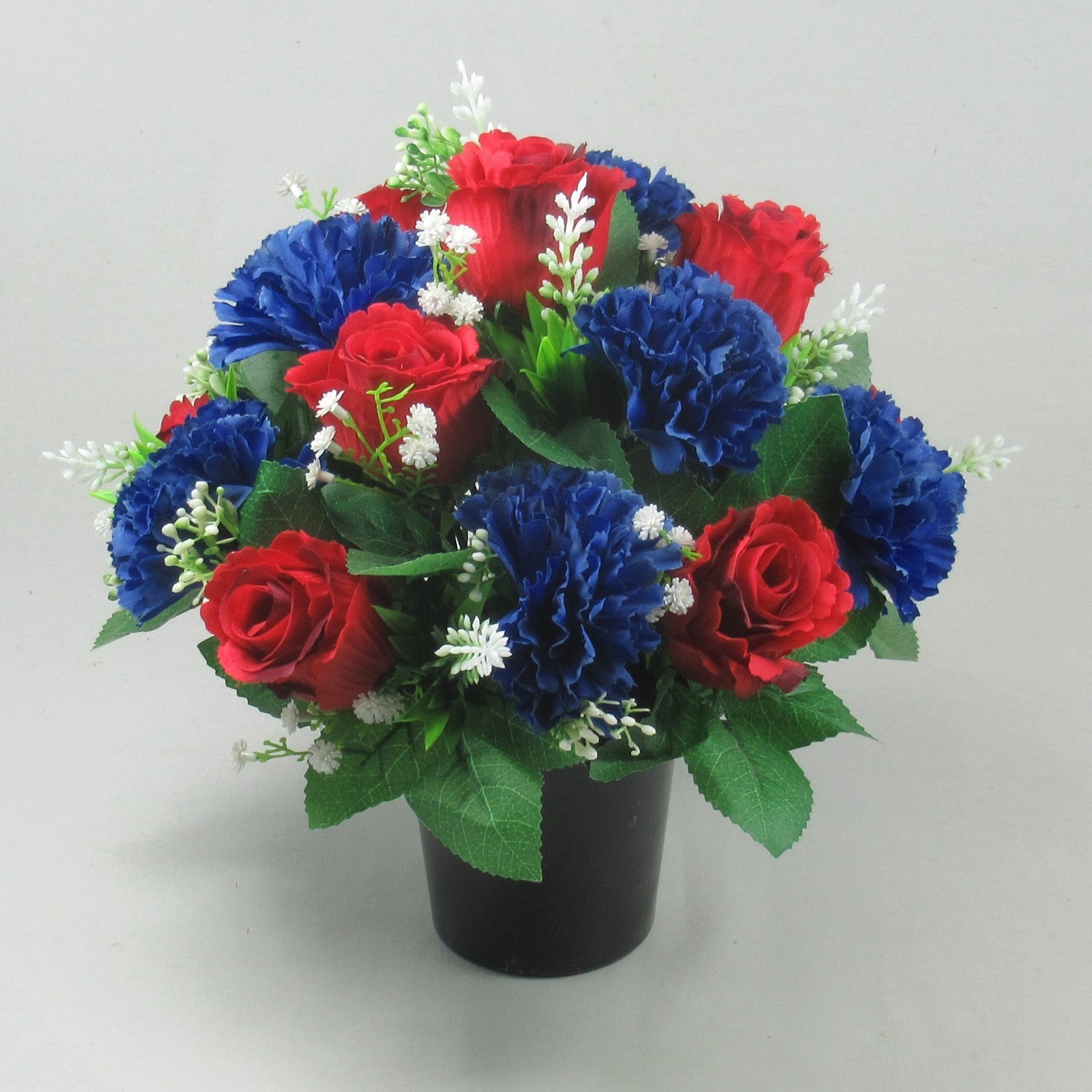 Cremation memorial flower pot with red roses, blue carnations, white sprigs, green foliage