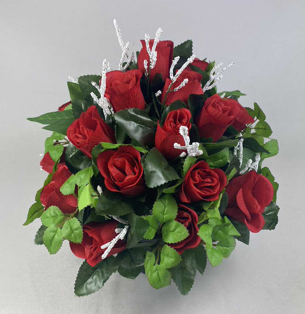 Artificial grave flower arrangement featuring red roses, green foliage, and silver glittery twigs.