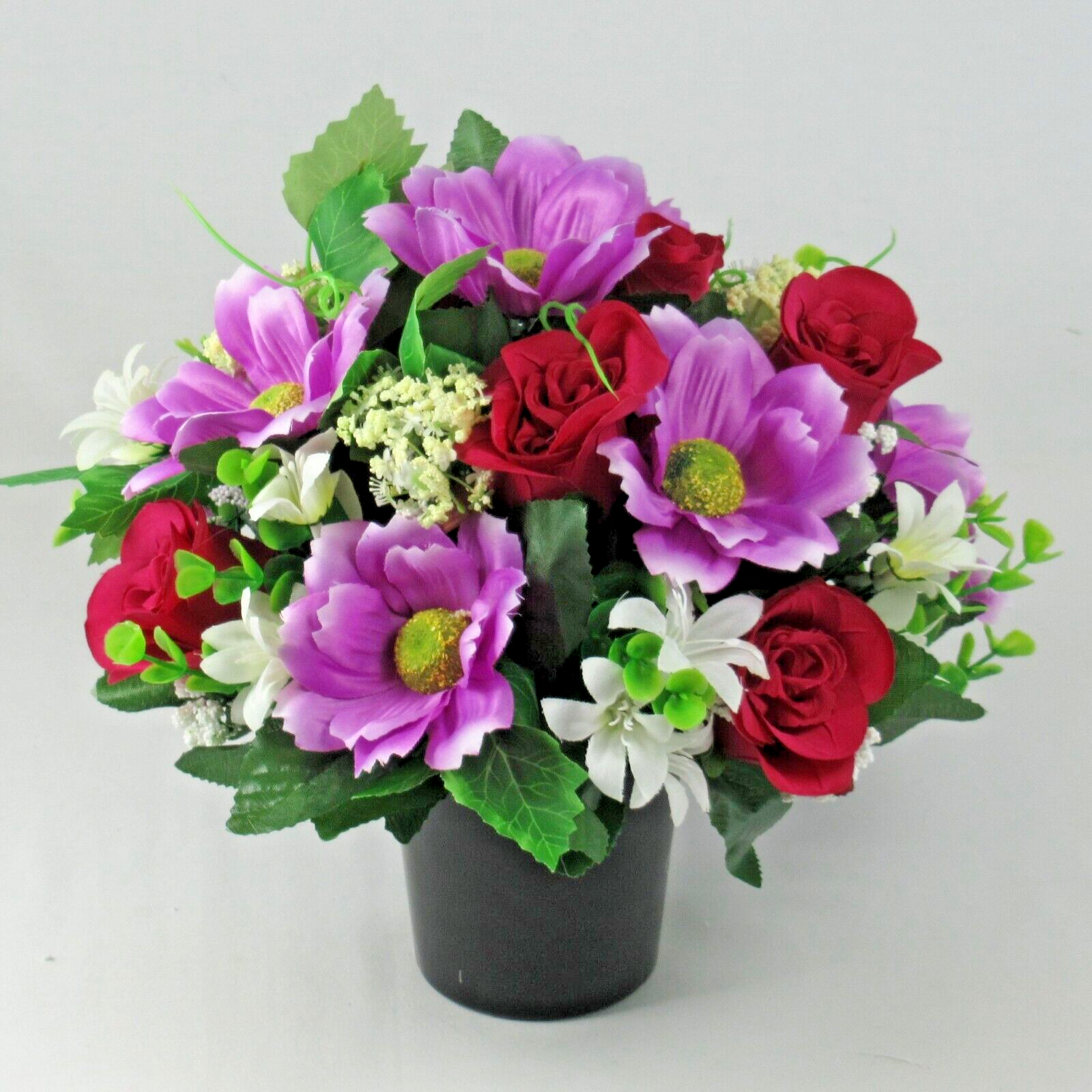 Purple and red artificial silk flower arrangement with white accents in black pot