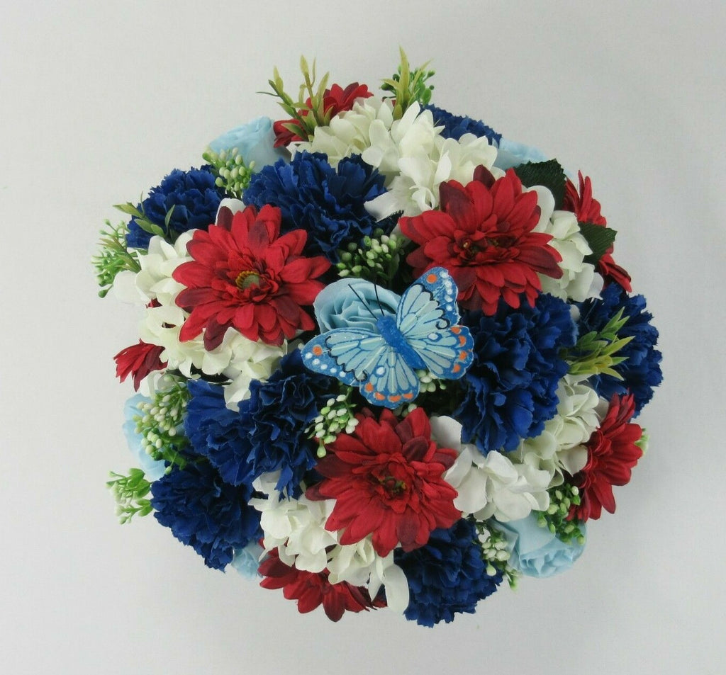 Artificial floral memorial bouquet with red, blue and white flowers plus light-blue butterfly