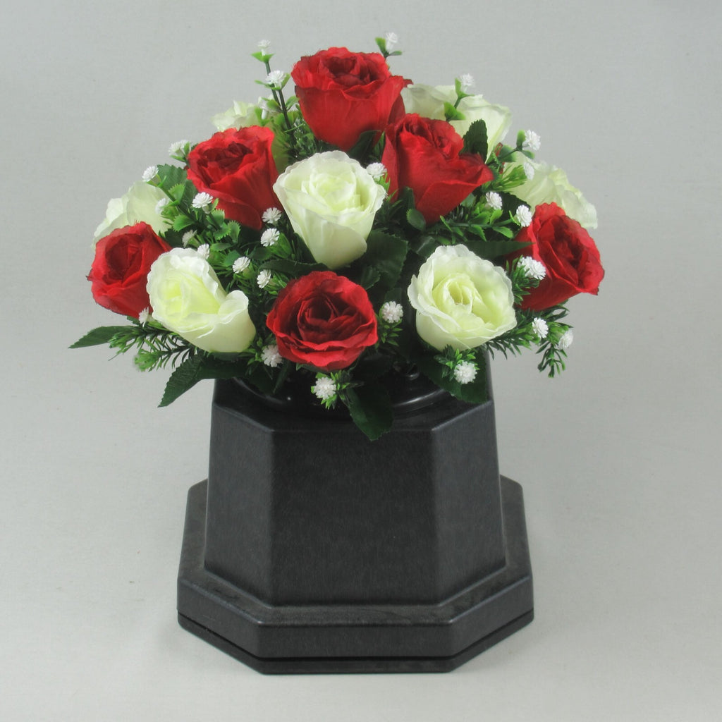 Artificial roses in black pedestal pot, red and ivory rose heads with green foliage