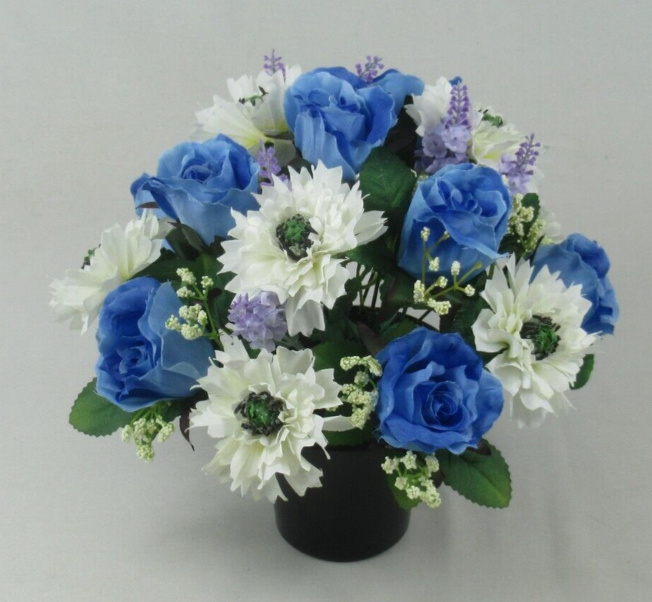 Side angle of artificial grave pot bouquet: blue roses, white flowers, purple sprigs, green leaves