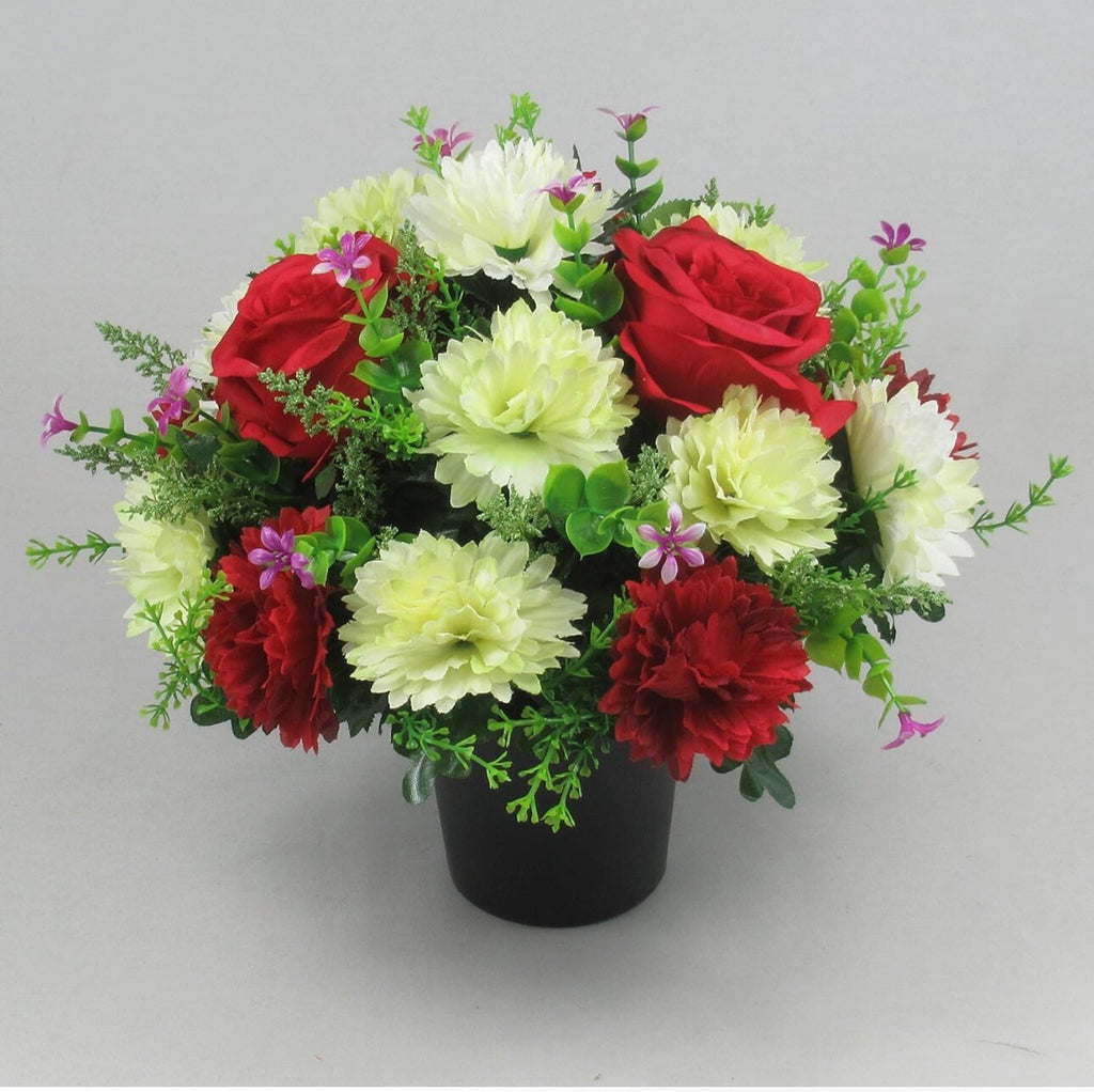 Artificial memorial crem pot flowers with red carnations, white blossoms, green foliage, black pot