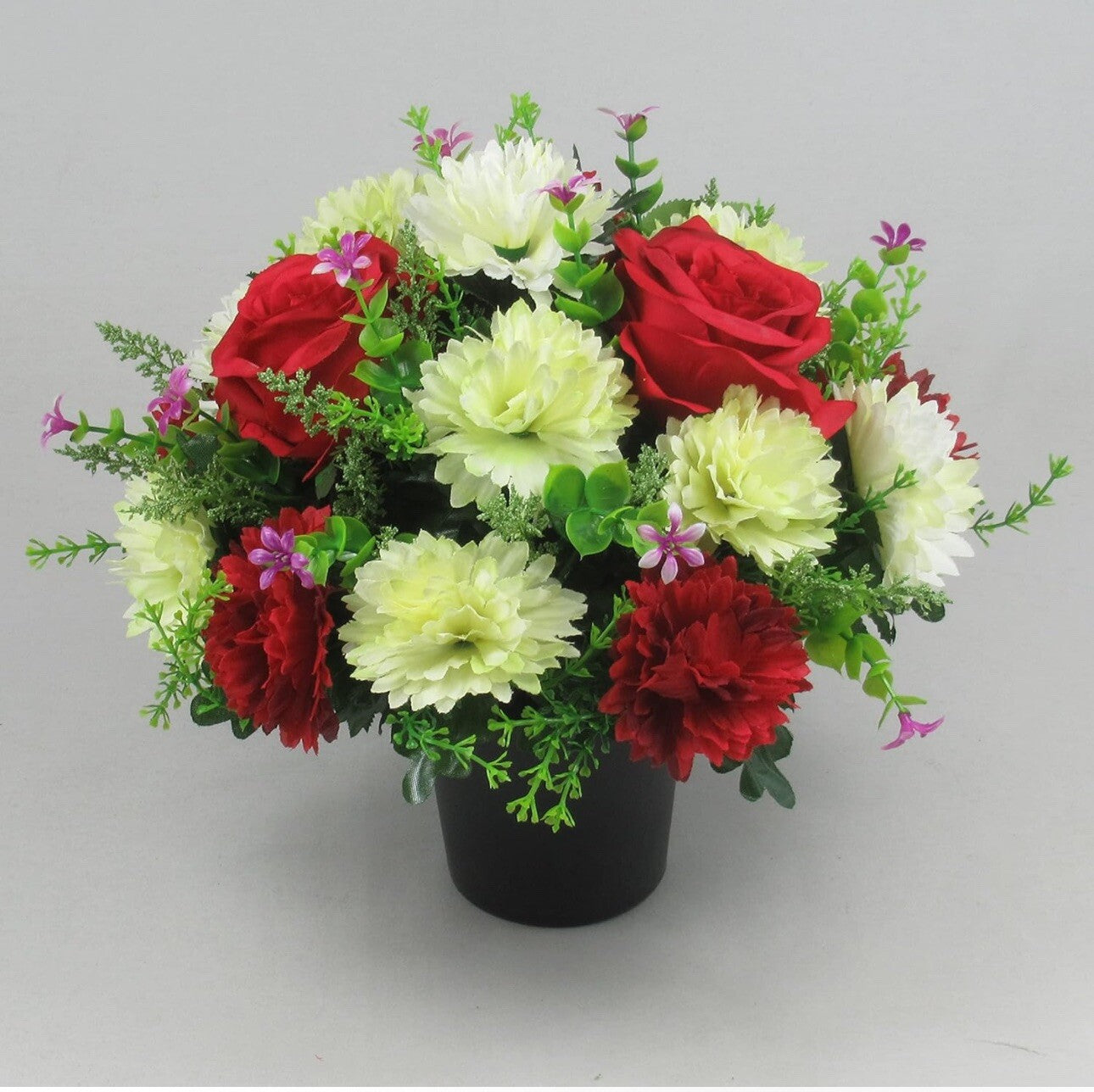Artificial memorial crem pot flowers with red carnations, white blossoms, green foliage, black pot