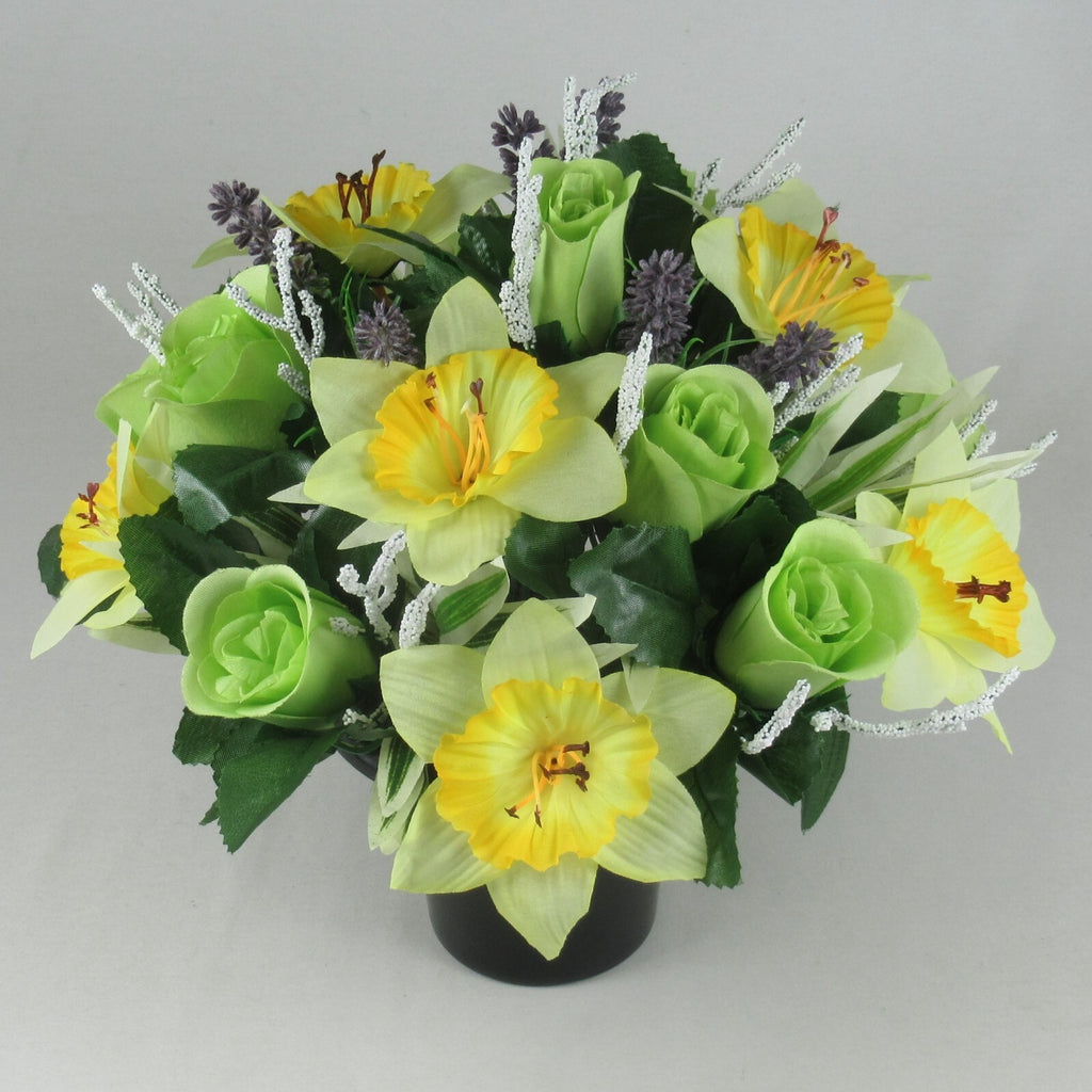 Front view artificial grave pot flowers: yellow daffodils, green roses, purple buds, white tinsel stems