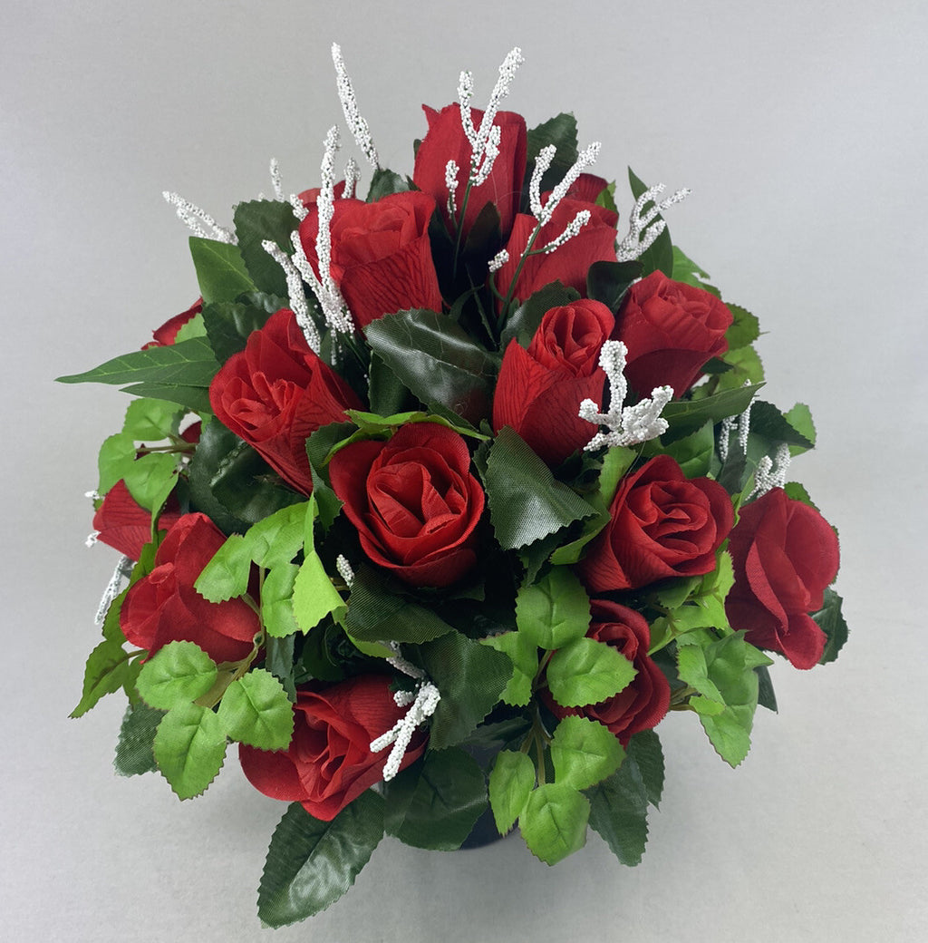 Large artificial grave flower arrangement with red roses, green leaves, silver twig stems.