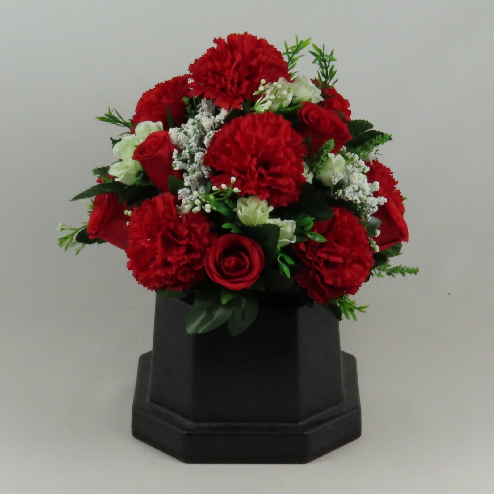 Artificial red rose and carnation memorial flowers with white filler, in dark hex vase