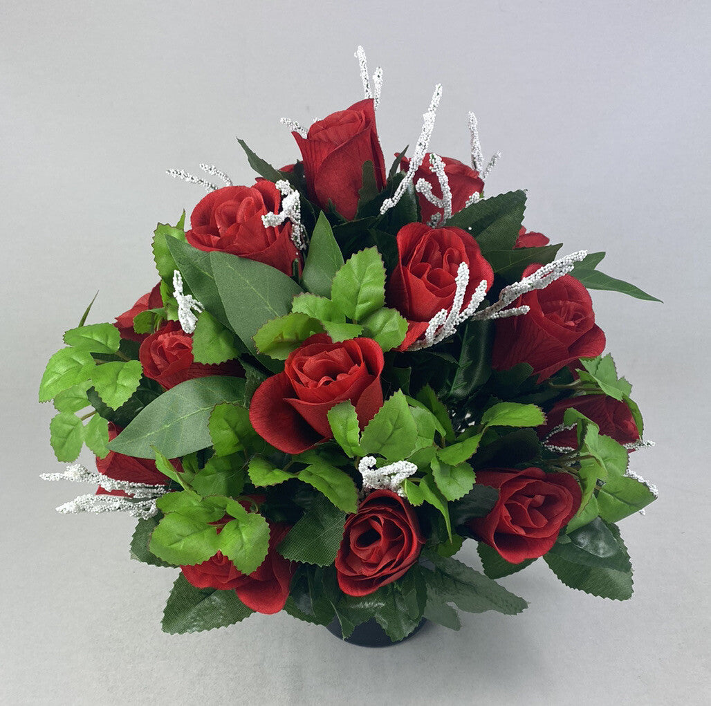 Artificial grave flower pot arrangement with red roses, green leaves, and silver sparkling branches.