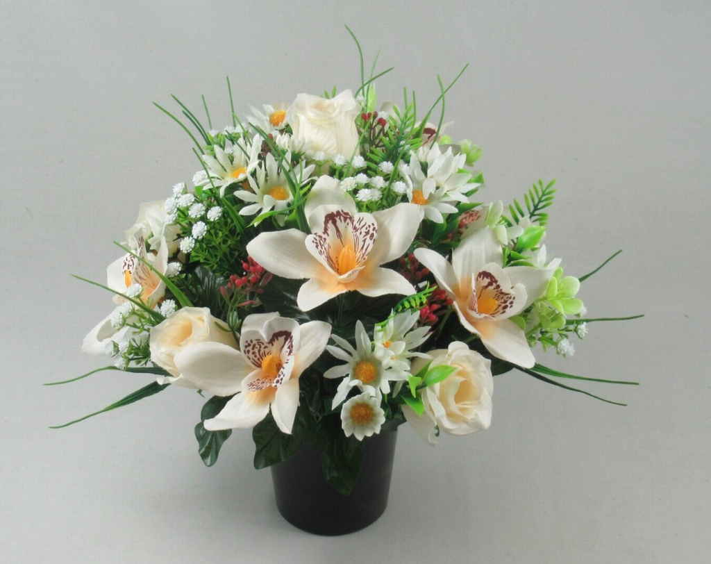 Artificial flower bouquet in black pot with large white orchids, orange centers, and roses
