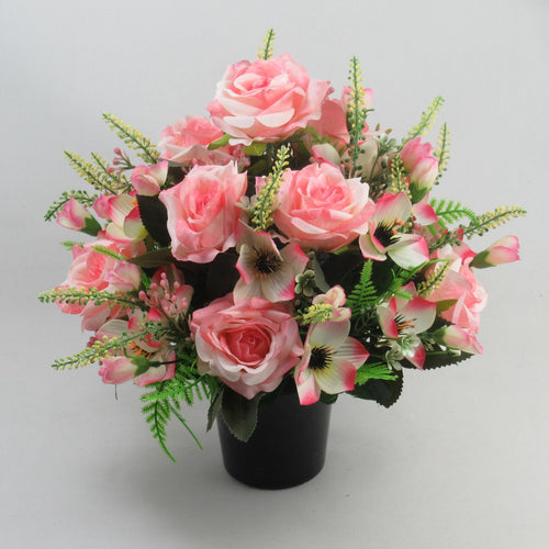 Pink rose blooms, pale pink lilies, and greenery in black vase centerpiece