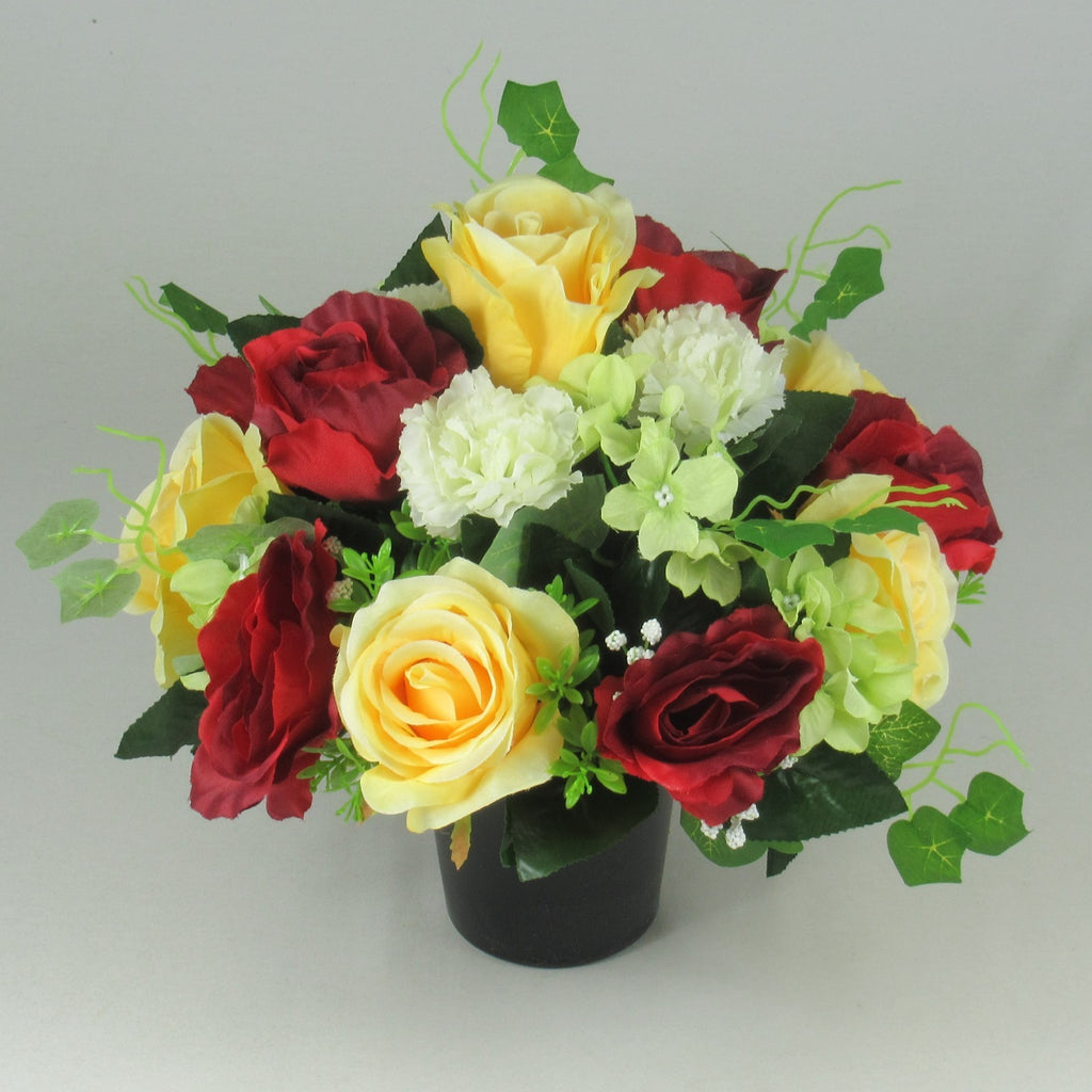Artificial grave bouquet in black vase: yellow and red roses with white and pale green blooms