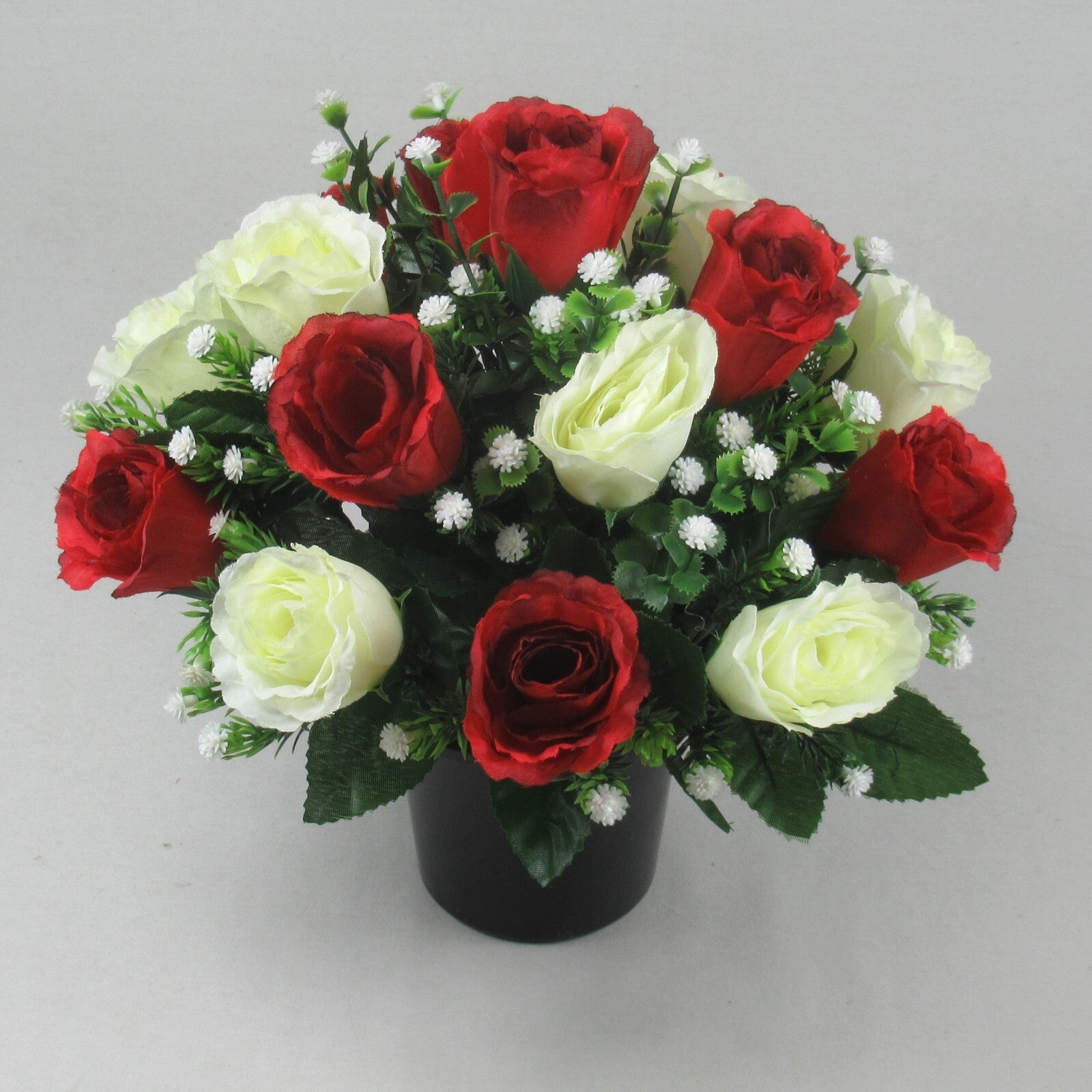 Front view of artificial grave flower arrangement: red and cream roses in black pot